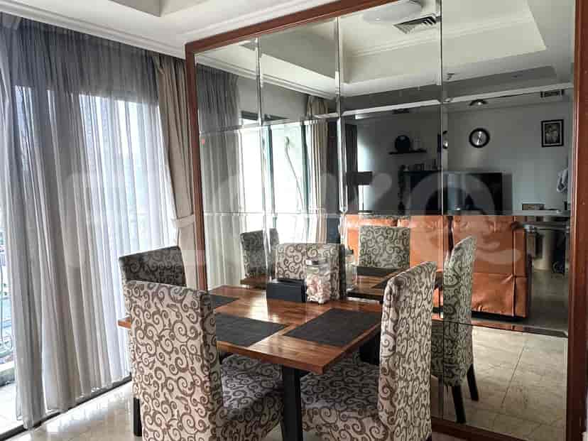 Dining area with wooden table, chairs, and mirror wall.
