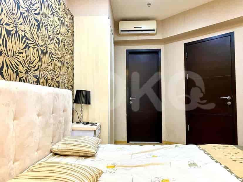 Bedroom with patterned wallpaper, large bed, and side table with lamp.