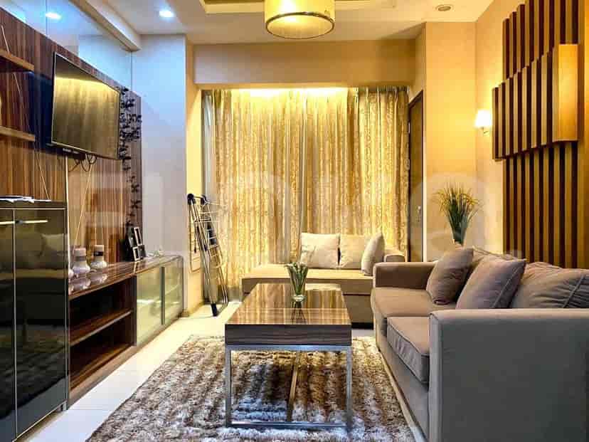 Modern living room with grey sofa, wall-mounted TV, and large window with curtains.