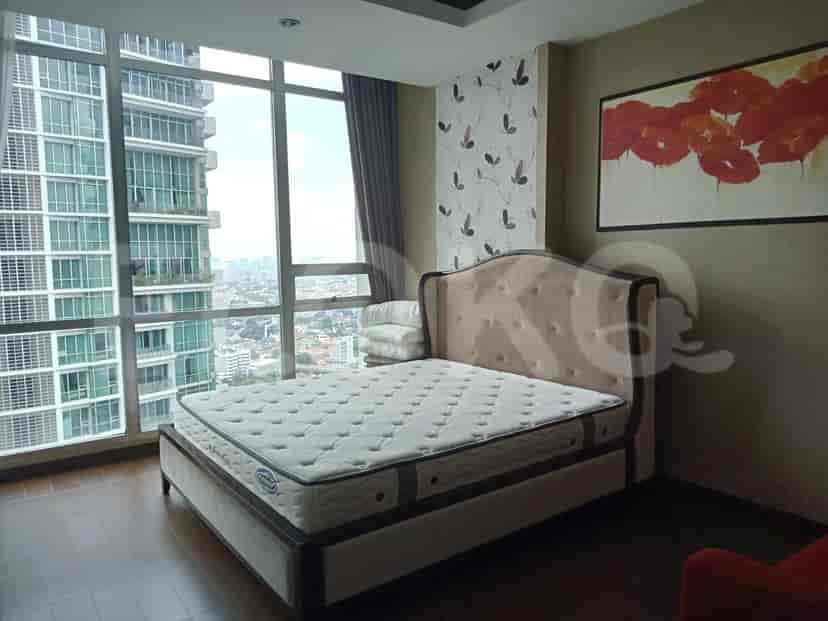 A bedroom with a bed, a large window, and art on the wall.