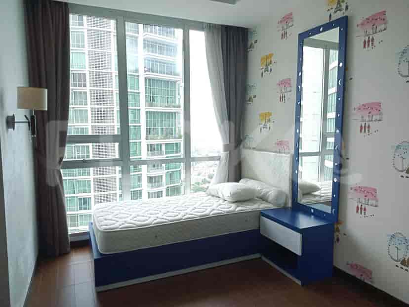 A bedroom with a blue-framed mirror, a bed, and a window with a view.