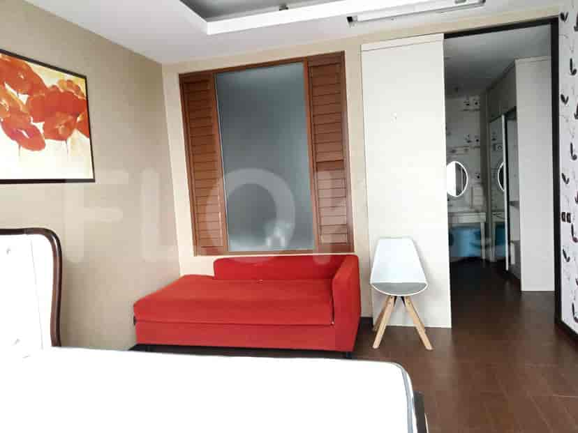 Bedroom with a red sofa, a window with shutters, and a painting.