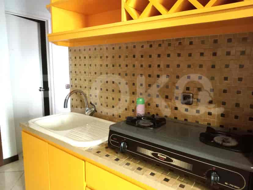 A small kitchenette with yellow cabinets and a gas stove.