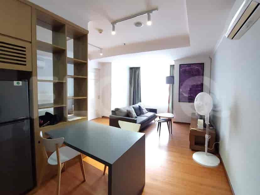 Area tempat tinggal modern dengan meja, sofa, dan penyimpanan built-in.