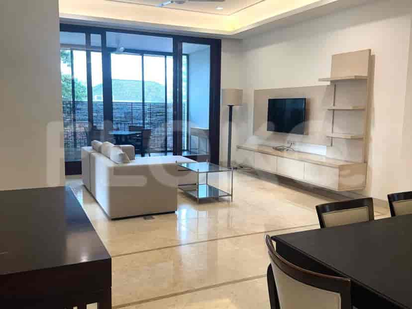 A modern living room with a beige sofa, wall-mounted TV, and glass coffee table.