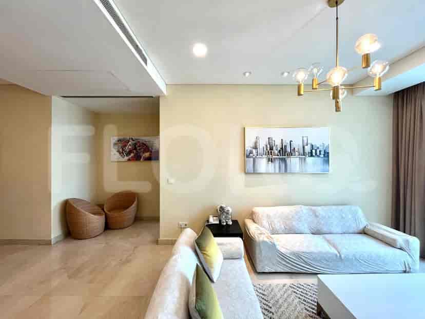 A modern living room featuring a grey sofa, wall art, and a chandelier.