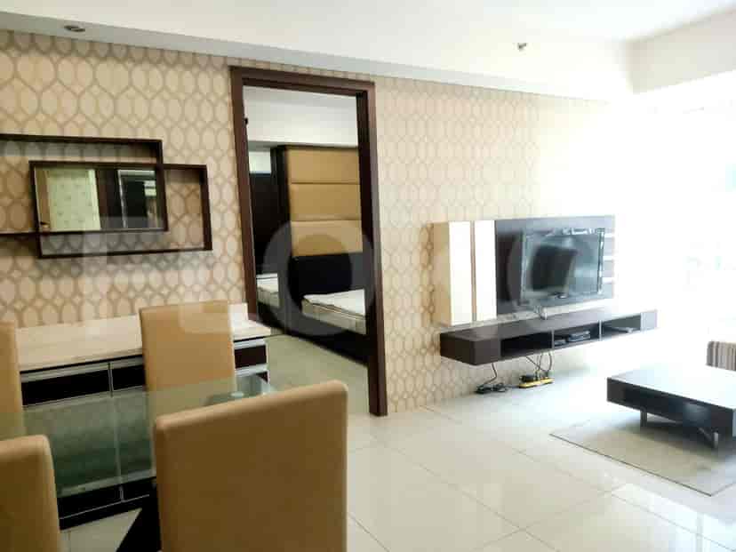 A combined living and dining room with a dining table, chairs, TV, and a view of the bedroom.