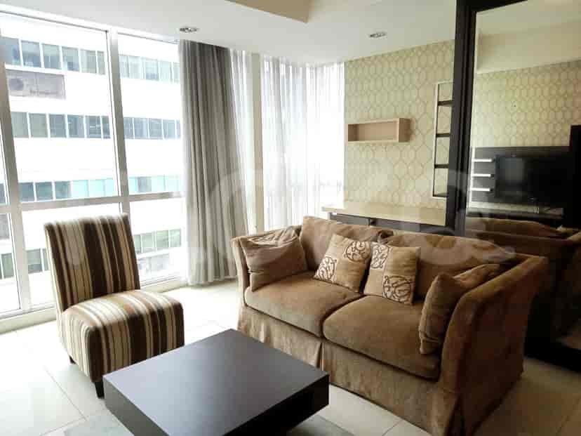 A living room with a brown sofa, striped chair, square coffee table, and large windows.