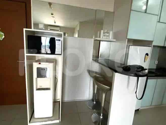 Combination of kitchen and living area with bar stools and a water dispenser.