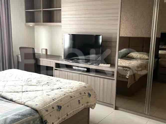 A bedroom with a bed, a desk, a TV, and a large mirror.