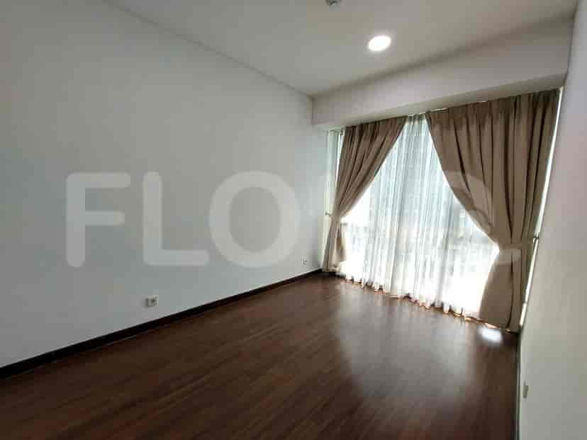 Bedroom with wooden flooring, large windows, and curtains.