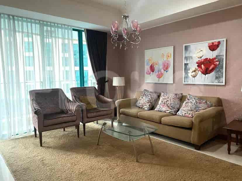 Living room featuring two armchairs, a sofa, a glass coffee table, and decorative wall art.