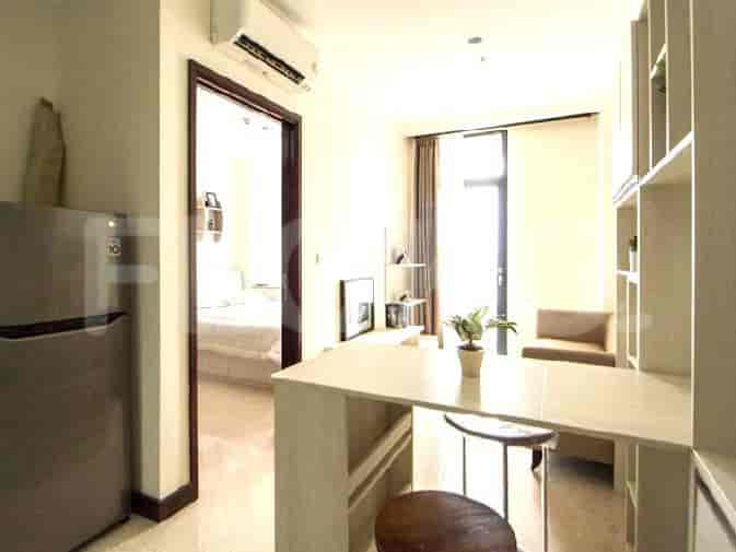 A compact living space with a bedroom visible through a doorway, a kitchenette, and a sitting area.