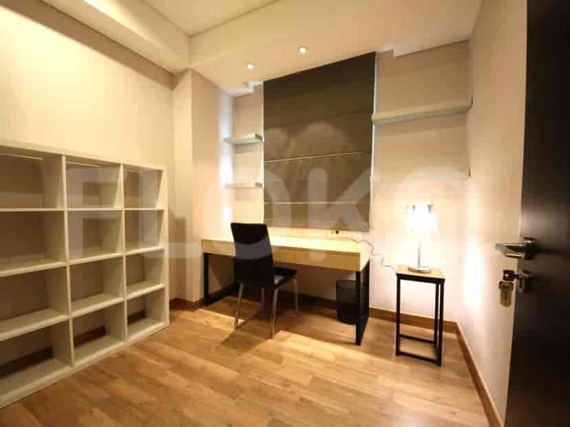 A dedicated office space with a desk, shelving, and wooden flooring.
