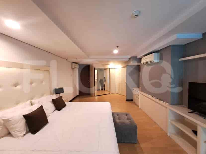 Kamar tidur utama yang besar dengan tempat tidur ukuran king dan unit hiburan built-in.