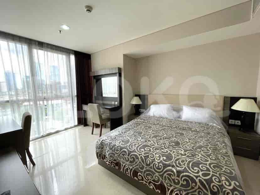 A bedroom featuring a bed, desk, and large window.