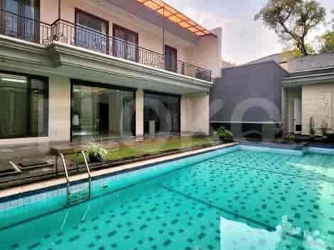 An outdoor swimming pool with a terrace, surrounded by the house and greenery.