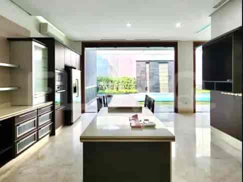 Modern kitchen with a large island, wooden cabinets, and a view of the swimming pool.