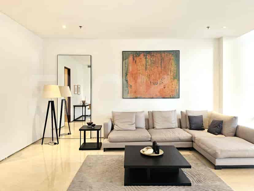 Ruang tamu modern dengan sofa berbentuk L, meja kopi, dan karya seni.