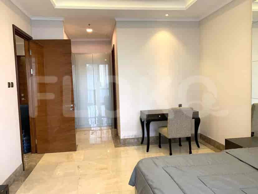 Bedroom with a desk, marble floor, and a bathroom door.