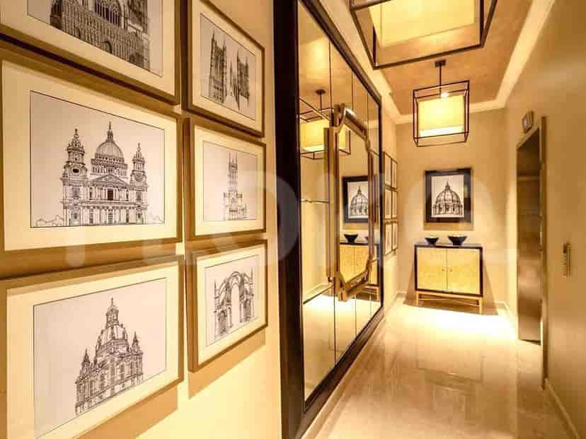 A luxurious hallway with framed artwork and a mirrored wall.