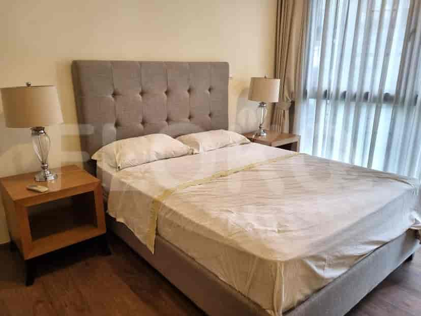 Kamar tidur yang menampilkan tempat tidur, meja samping tempat tidur dengan lampu.
