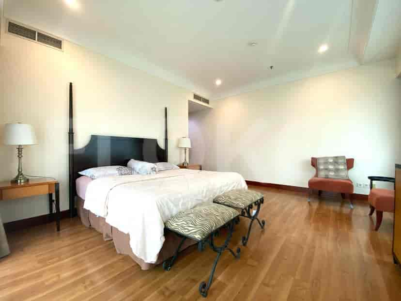 Kamar tidur utama dengan tempat tidur ukuran king, lantai kayu, dan kursi.