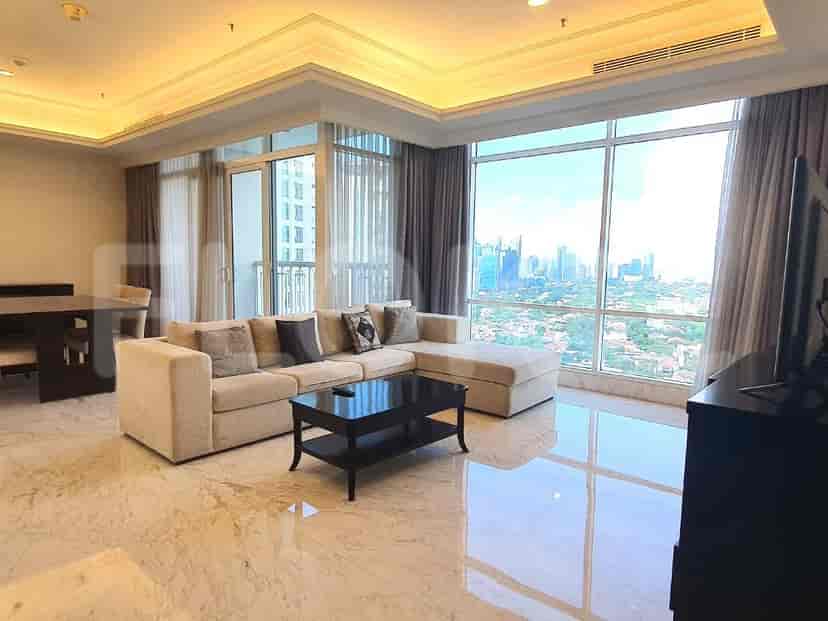 Spacious living room with an L-shaped sofa, a black coffee table, and large windows offering a city view.