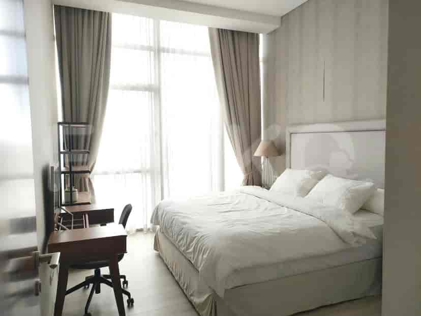 A modern bedroom with a bed, desk, and large windows offering ample natural light.
