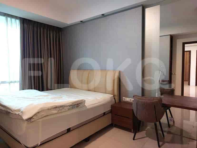 A bedroom with a bed, desk, and window with curtains.
