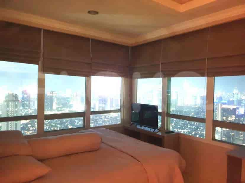 Bedroom with large windows, city view, and TV.