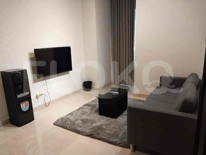 Living room with a grey sofa, TV, rug, and water dispenser.