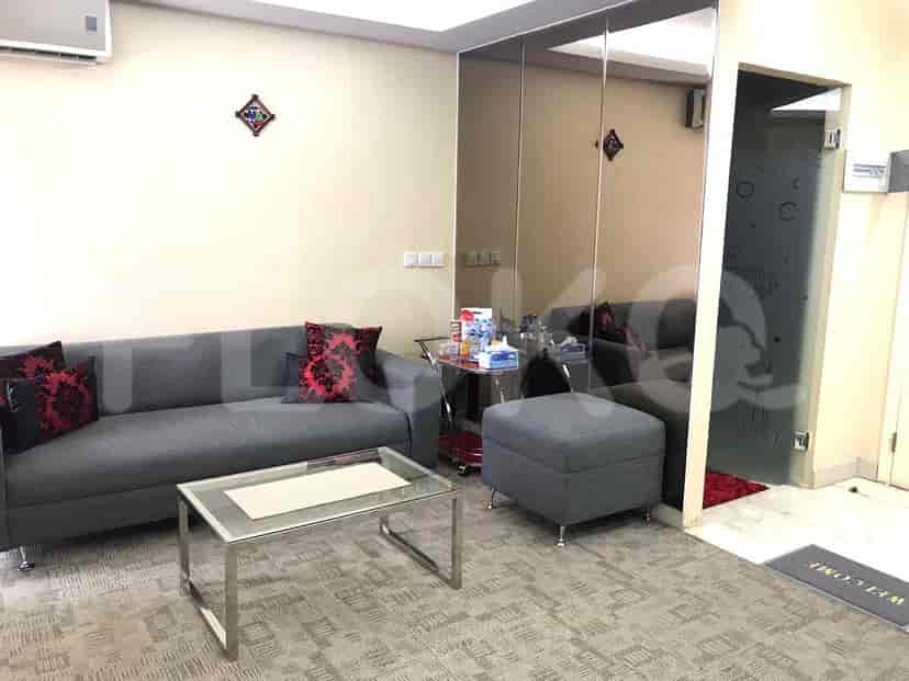 A modern living room with a grey sofa, glass coffee table, and mirrored wall.