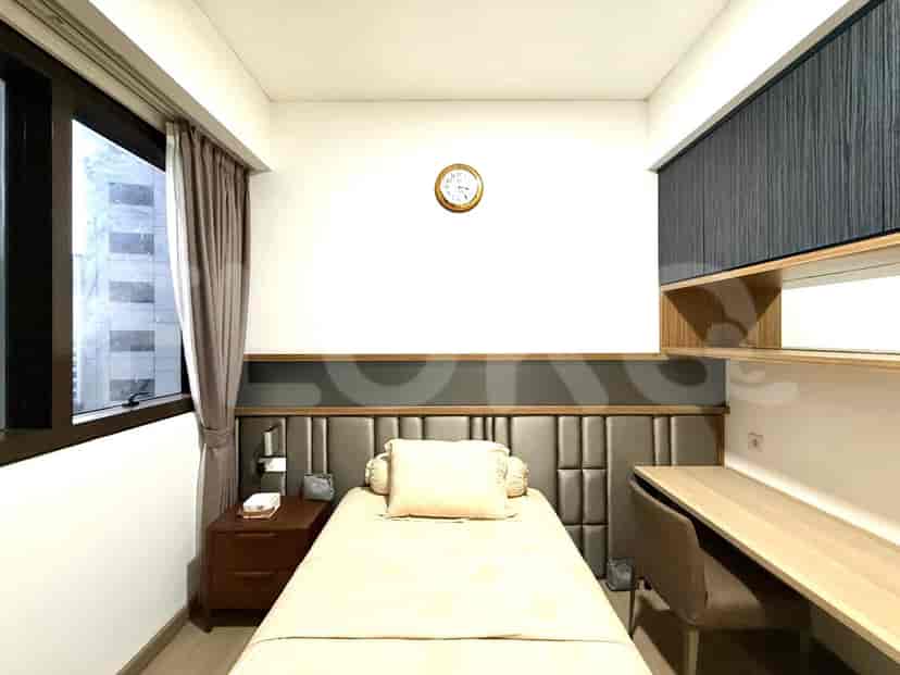Ruangan ringkas dengan tempat tidur tunggal, meja, dan rak built-in.