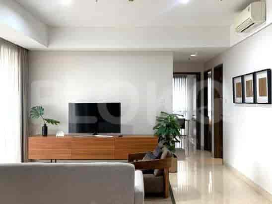 A living room with a TV stand, a television, a sofa, and a large window with curtains.