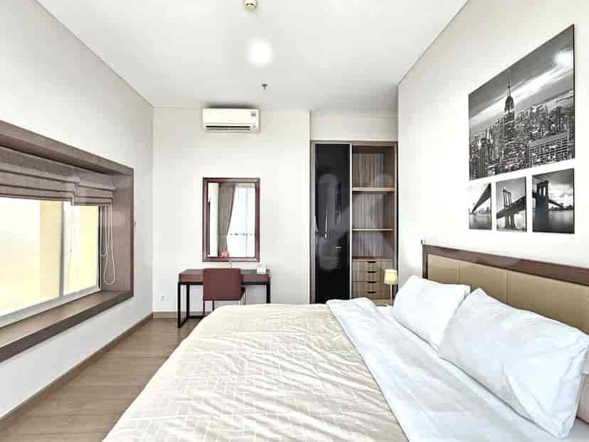 A bedroom with a bed, a desk, a mirror, and a window.