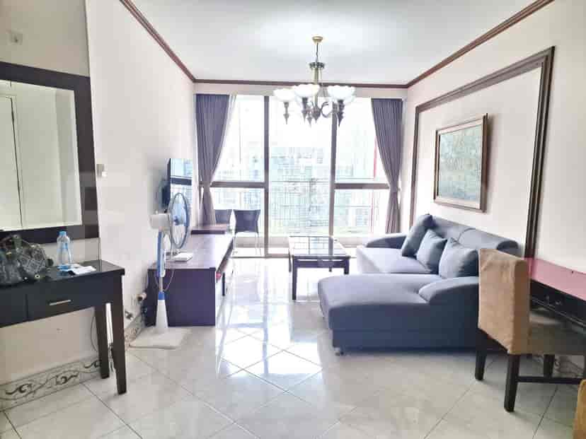 A living room with a grey sectional sofa, a coffee table, a television, and large windows.