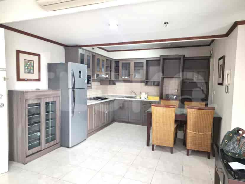 A kitchen with grey cabinets, a stainless steel refrigerator, and a dining set.