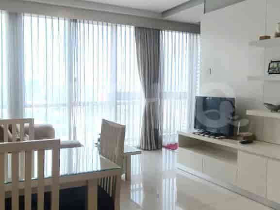 A living room area featuring a large window with curtains and a television on a console.