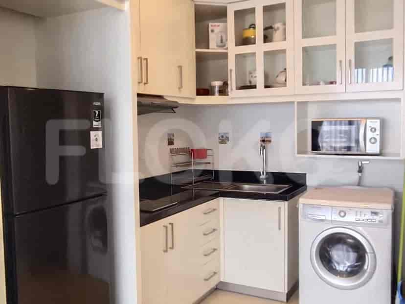 A compact kitchen with white cabinets, a black countertop, a refrigerator, a microwave, and a washing machine.