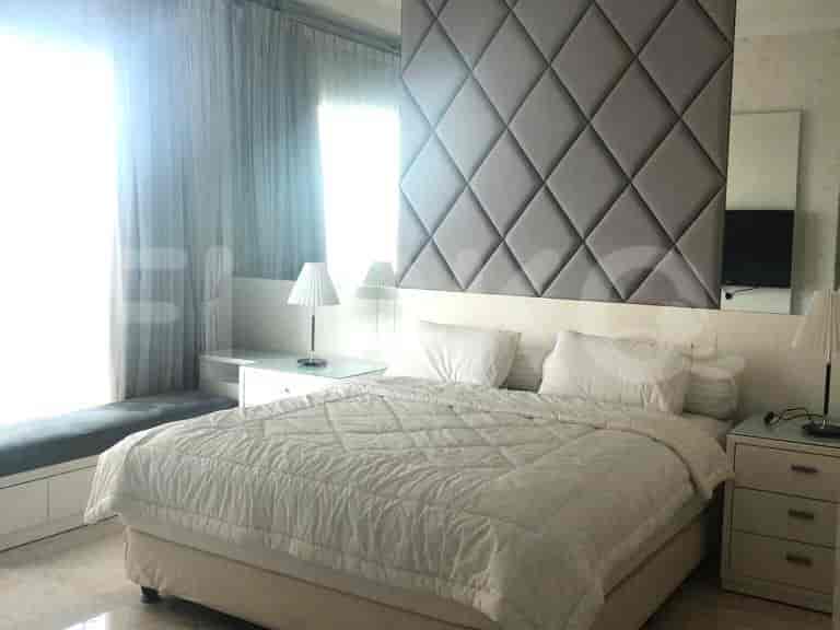 A bedroom with a large bed, nightstands, lamps, and a textured headboard.