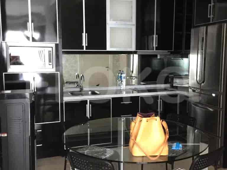 A modern kitchen with black cabinets, stainless steel appliances, and a glass dining table.