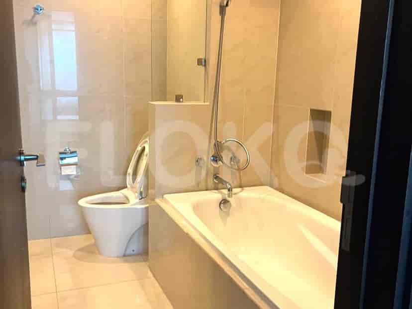 A clean bathroom with a bathtub, toilet, and beige tiled walls.