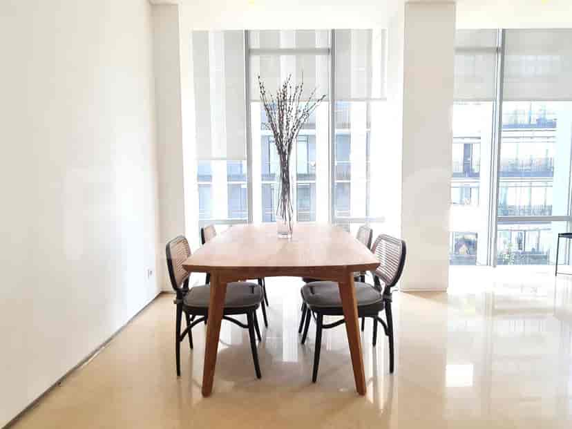 A dining room with a wooden table and chairs, set against a backdrop of large windows.