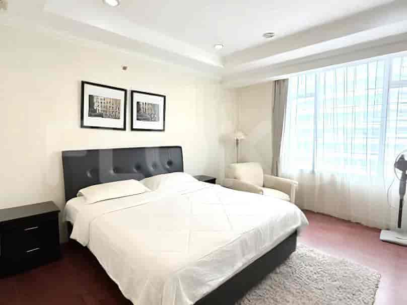 A master bedroom with a king-size bed, two nightstands, framed artwork, and a large window.