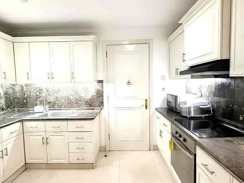 A closed kitchen with white cabinets, granite countertops, and a black electric stove.