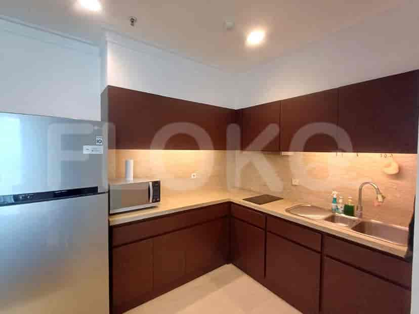 A kitchen with dark wood cabinets, granite countertops, a stainless steel refrigerator, and a microwave.