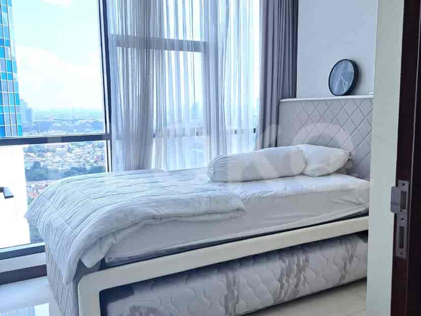 A bedroom with a queen-size bed, a pull-out trundle bed, and large windows with sheer curtains.