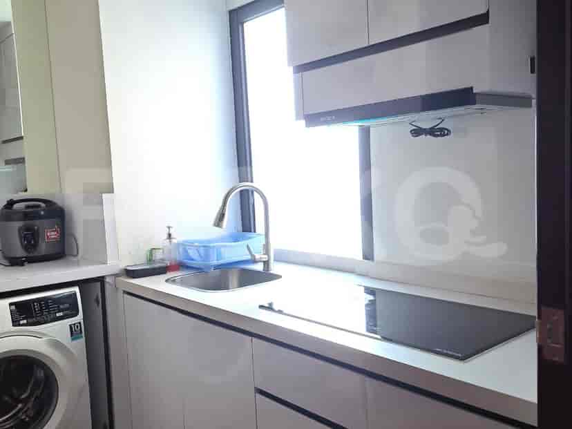 A compact kitchen with a sink, electric stove, range hood, and a washing machine.