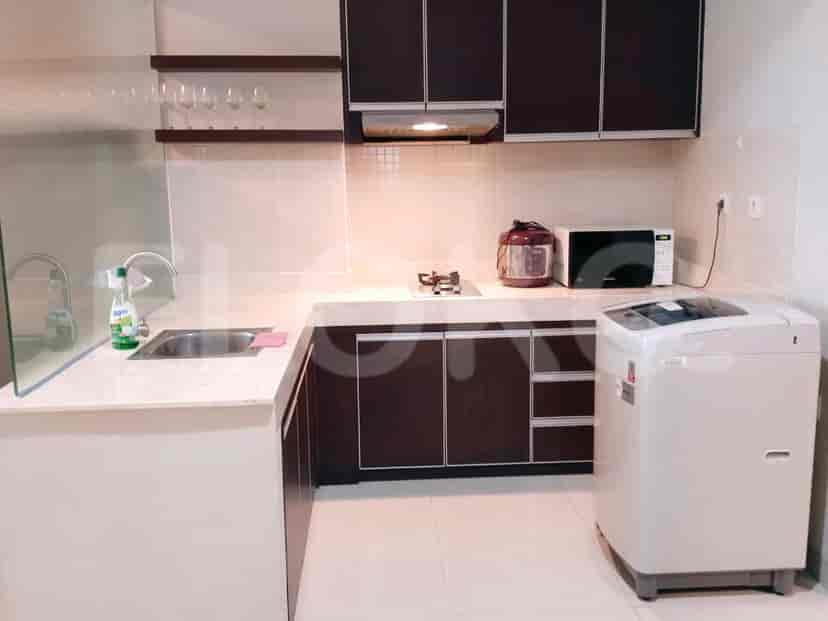 A modern kitchen with dark cabinets, a gas stove, microwave, and a washing machine.